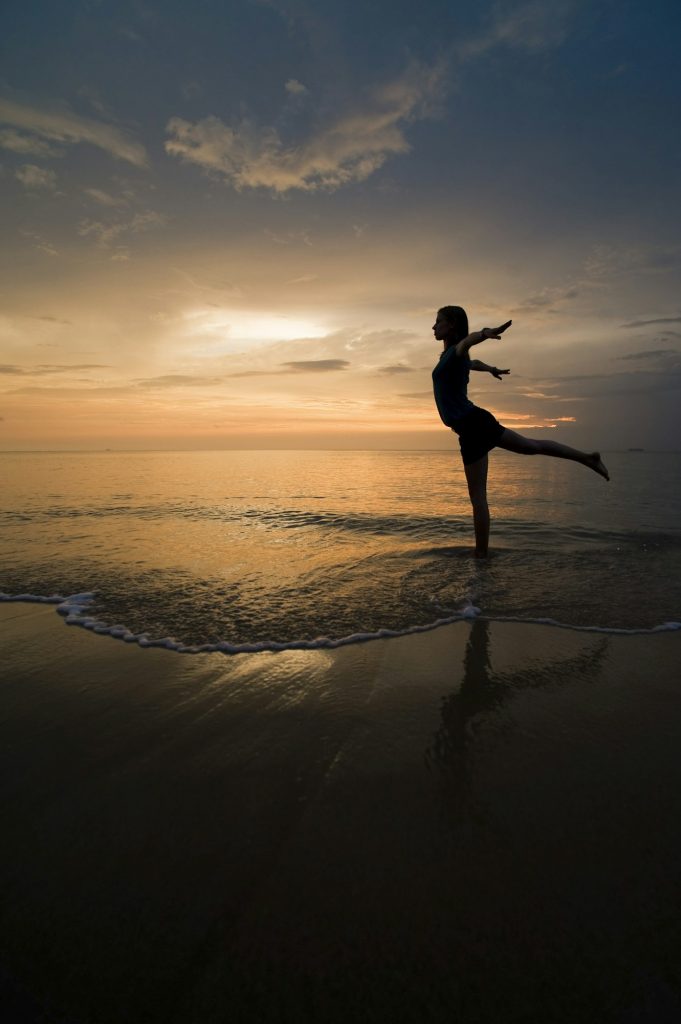 A young woman at the beach at sunset doing yoga exercises, Thai Islands at Koh Samui, Thailand, Sout