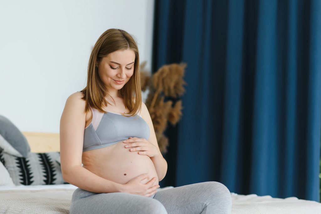 The concept of pregnancy and waiting - a happy pregnant woman holds her hands stomach